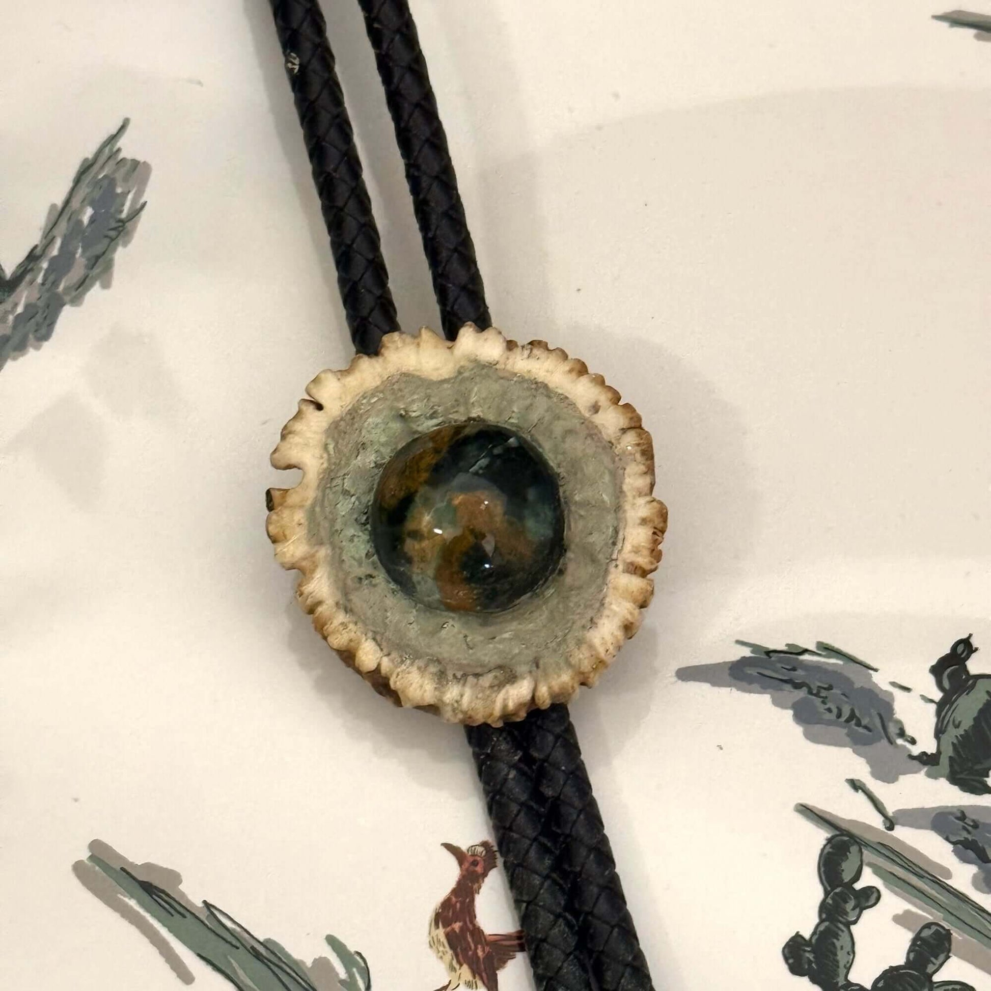 Bolo tie with a textured circular design on a white background with illustrations