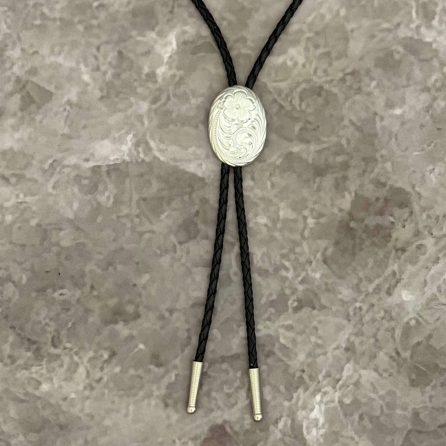 Bolo tie with silver concho on a textured gray background