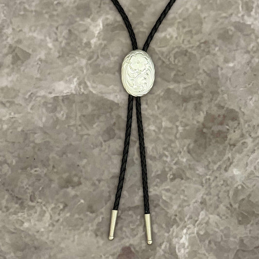 Bolo tie with silver concho on a textured gray background