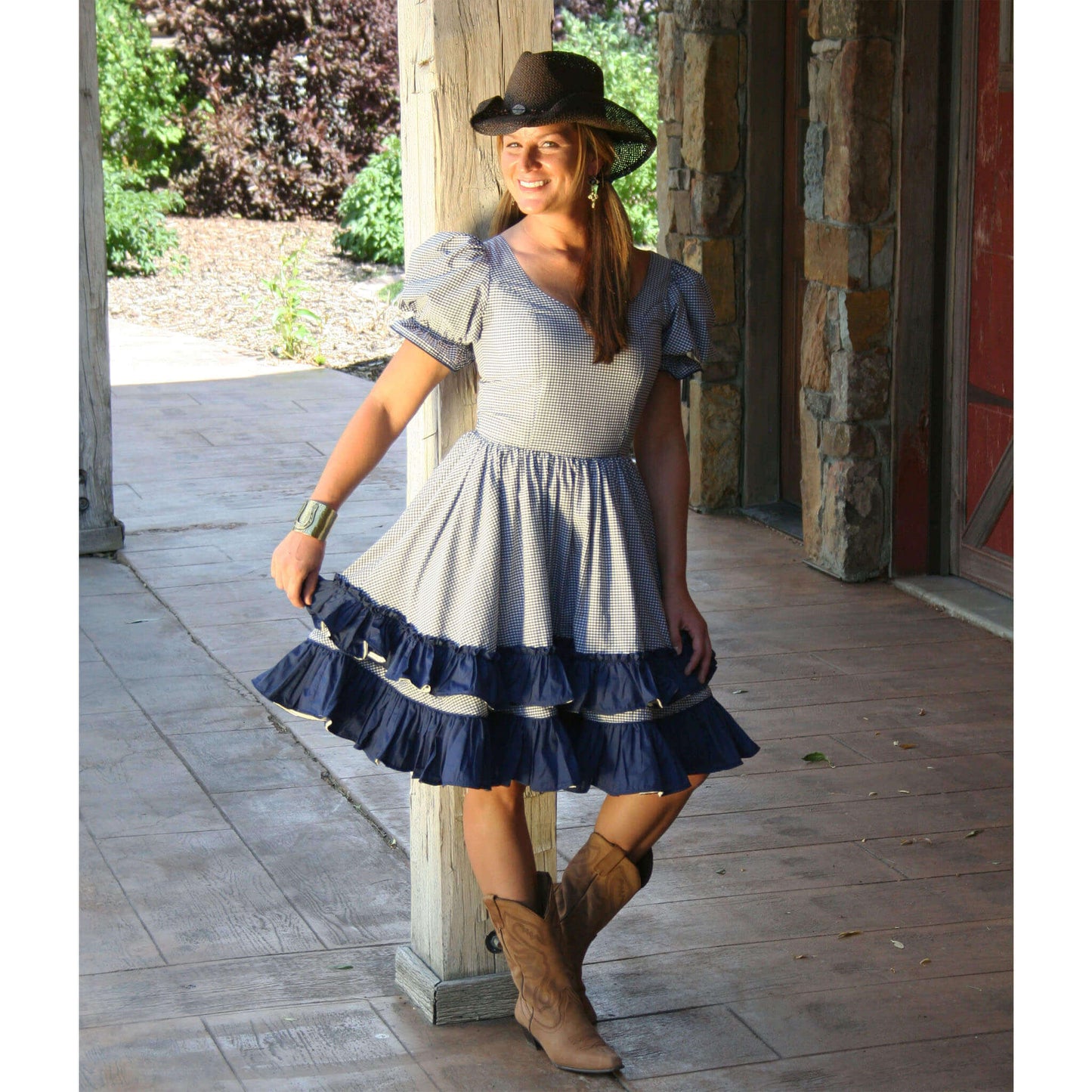 Woman in Barn Dancer Country Dress with ruffles and cowboy hat, posing outdoors, perfect for barn dances.