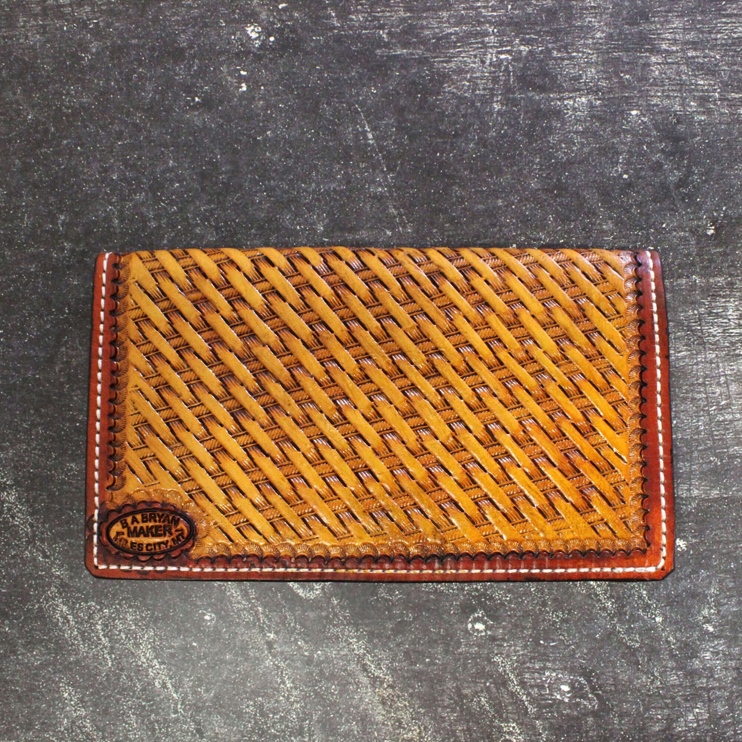 Brown leather cardholder with woven pattern on a dark textured surface