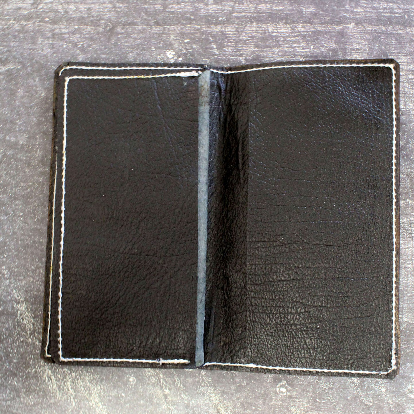 Black leather wallet open on a gray surface