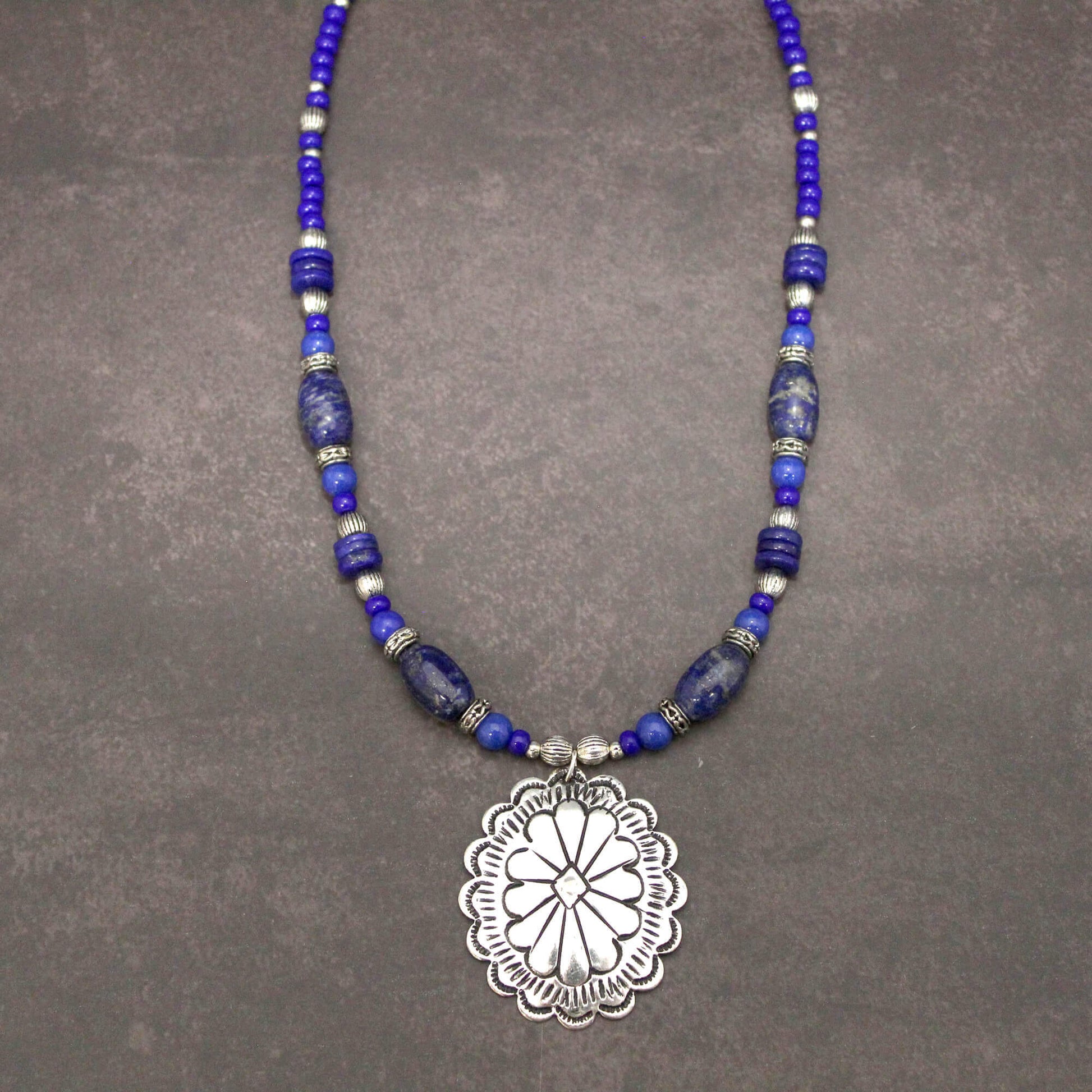 Perfect with Denim! A silver concho with Lapis Lazuli stones. The benefits consist of a powerful intense blue stone used to open minds and give enlightenment. This measures 18″ and an additional 1.75 pendant with an extender.  Each piece is unique and may vary slightly.