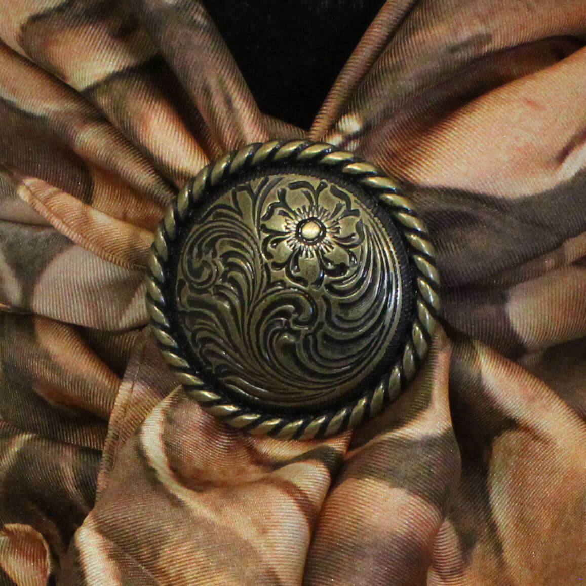 Decorative button with intricate design on a brown fabric background