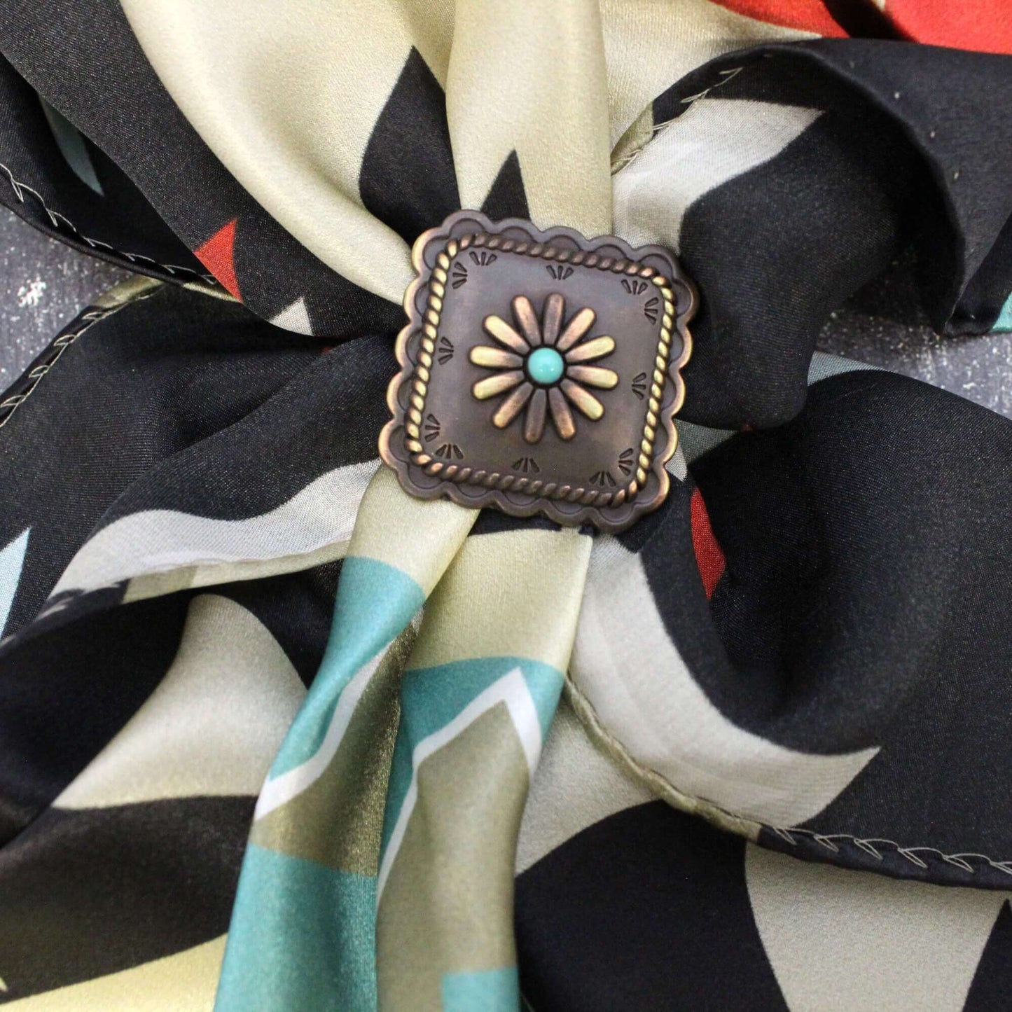 Beautiful square scarf slide with scalloped edges and a turquoise center with windmill like design. Measures 1-1/2" with back loop for a modern decorative ring to secure your western silk scarf.