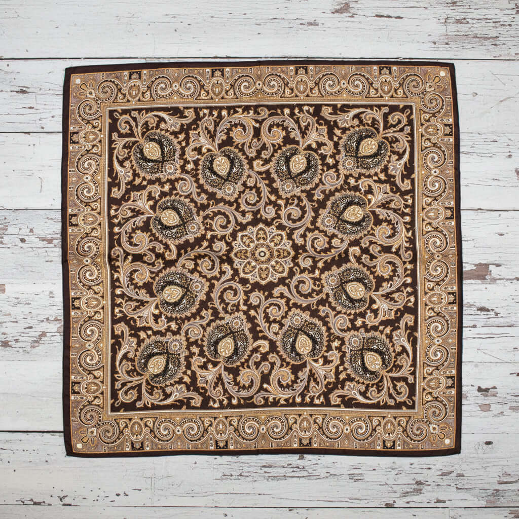 Decorative square western paisley silk scarf with intricate pattern on a gray floor