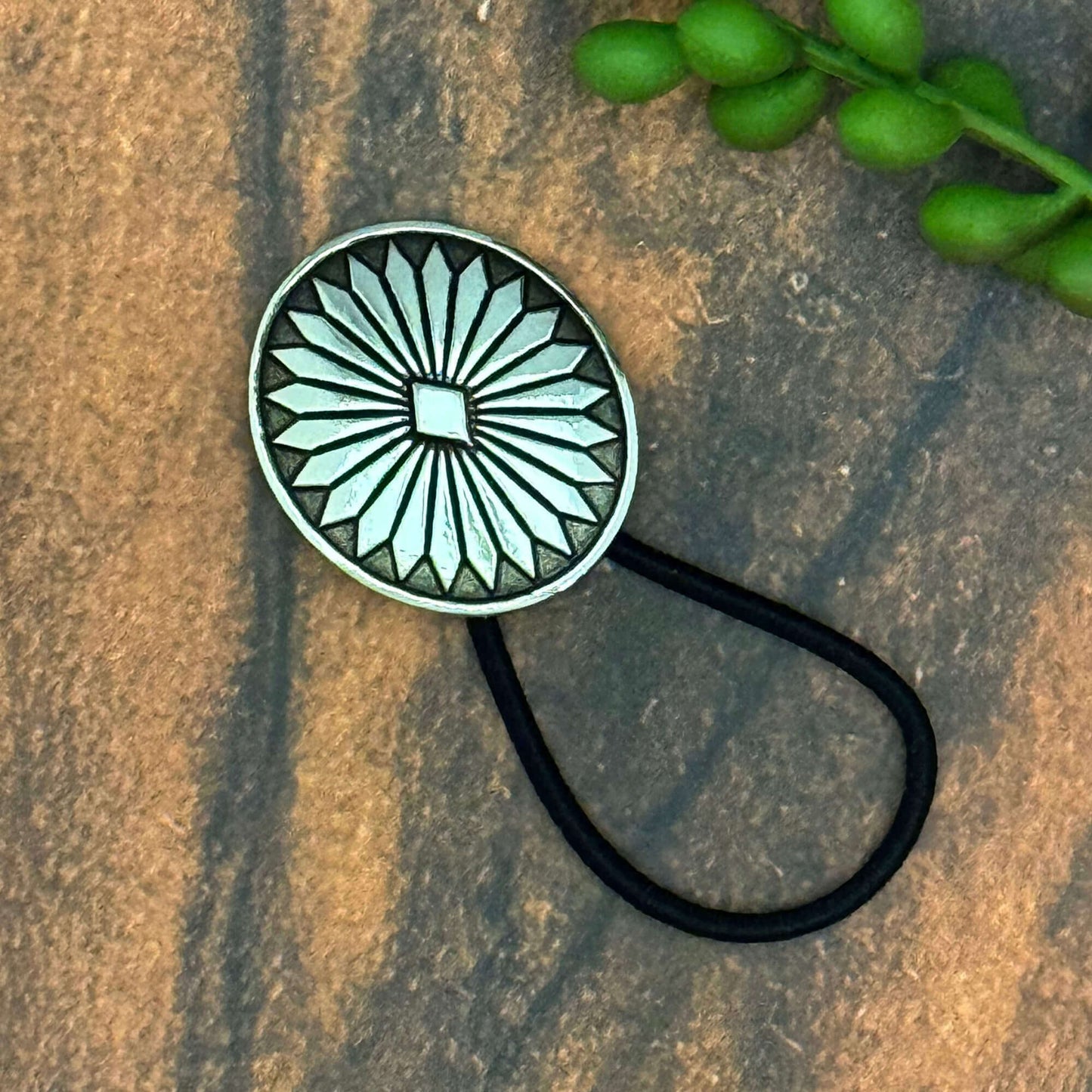 Vintage German silver-plated concho ponytail holder on a black elastic band, decorative hair accessory.