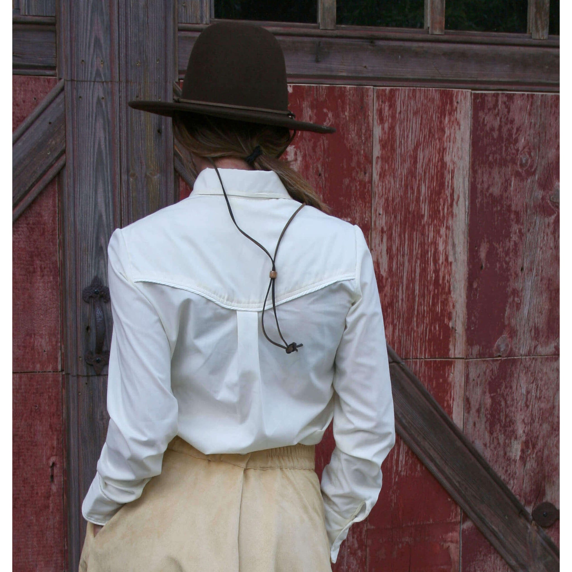Back view of women's Corral Western blouse with round collar and unique keyhole cuffs, paired with a stylish hat.