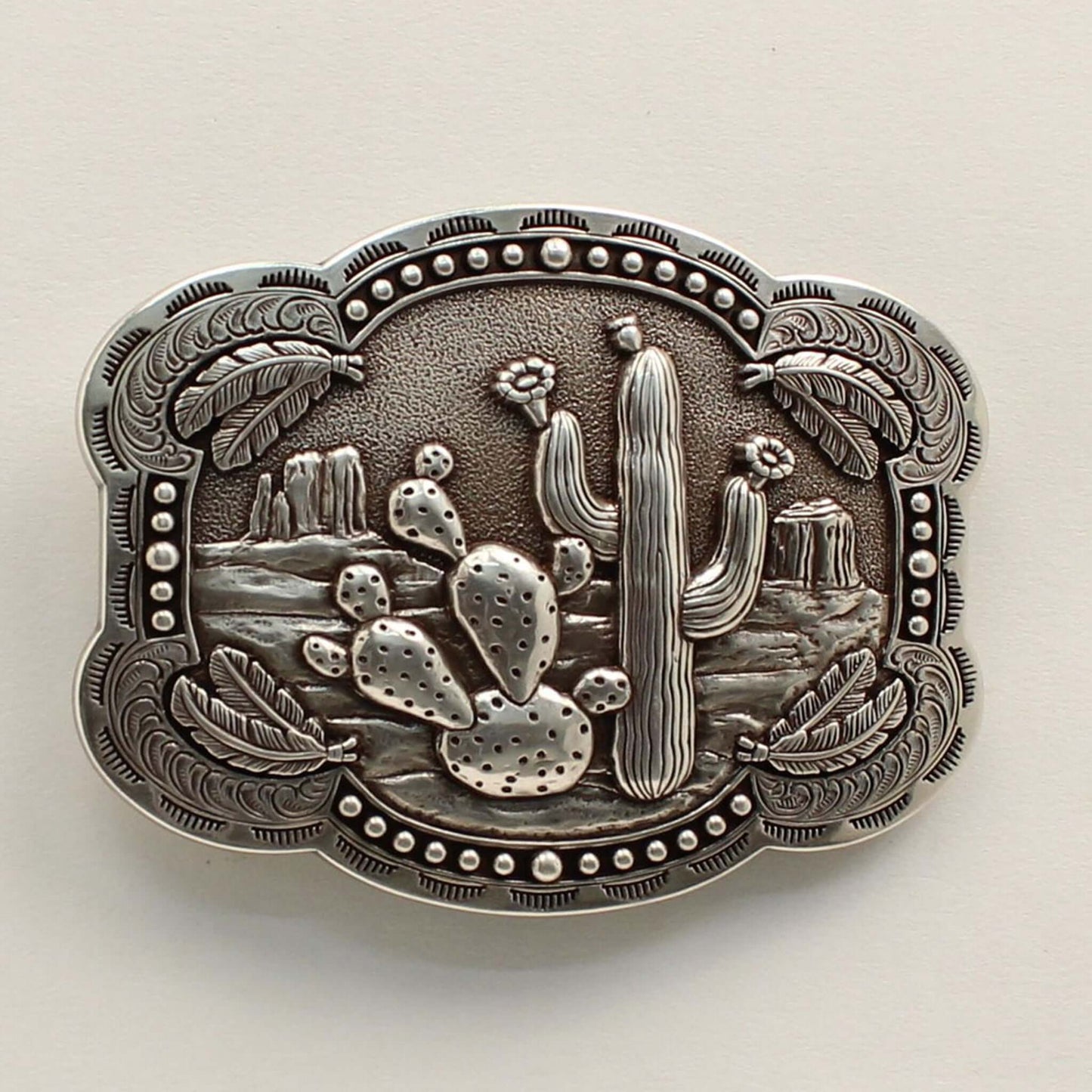 <span data-mce-fragment="1">This rectangle western buckle features a smooth edge with an antique desert scenery in the background with stamped cactus. There is western scrolling and feathers on the corners and small dots on the edges. </span><span data-mce-fragment="1" lang="EN-US">Measures: 3-3/4 x 3-1/4 Imported</span>