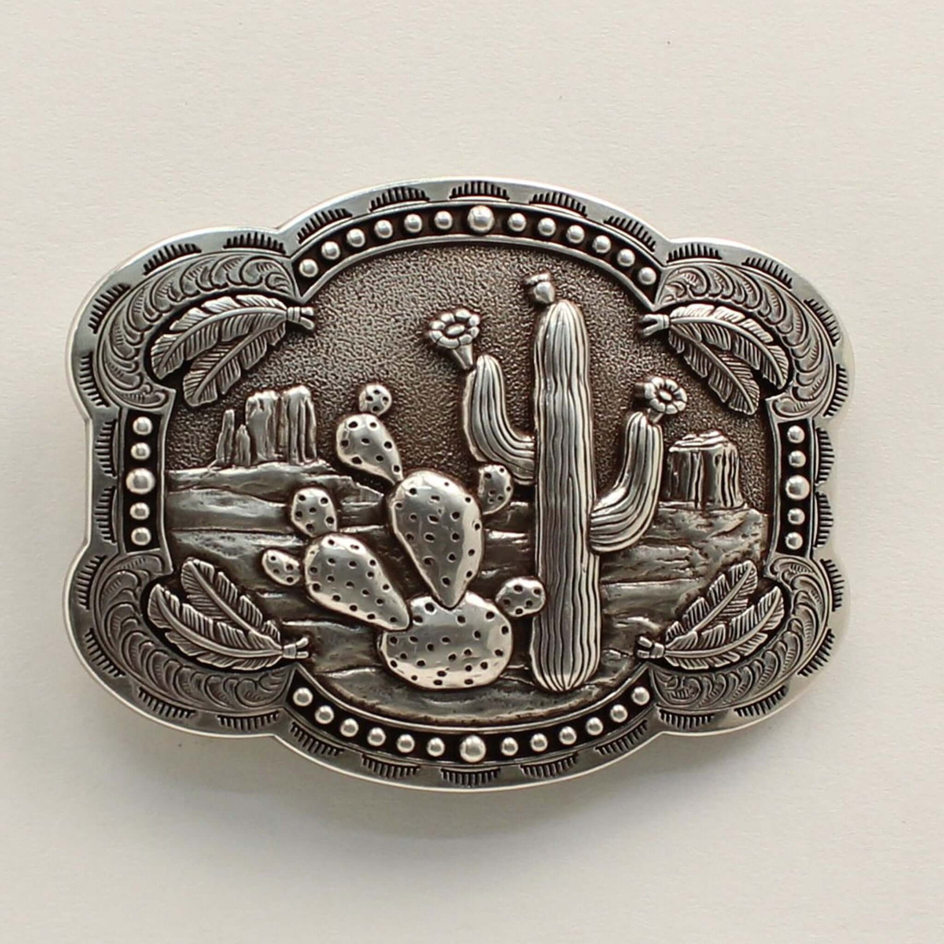 <span data-mce-fragment="1">This rectangle western buckle features a smooth edge with an antique desert scenery in the background with stamped cactus. There is western scrolling and feathers on the corners and small dots on the edges. </span><span data-mce-fragment="1" lang="EN-US">Measures: 3-3/4 x 3-1/4 Imported</span>