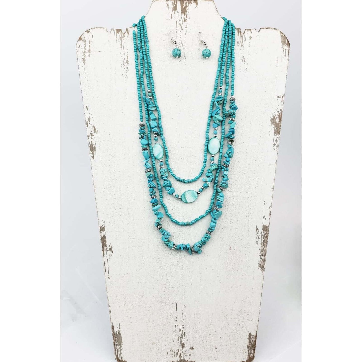 For turquoise and ocean lovers alike. Four layered strands of mag turquoise beads and stone. Longest strand measures 22″ with lobster claw clasp and extension chain. Matched with hypoallergenic ear wires holding a mag turquoise bead.