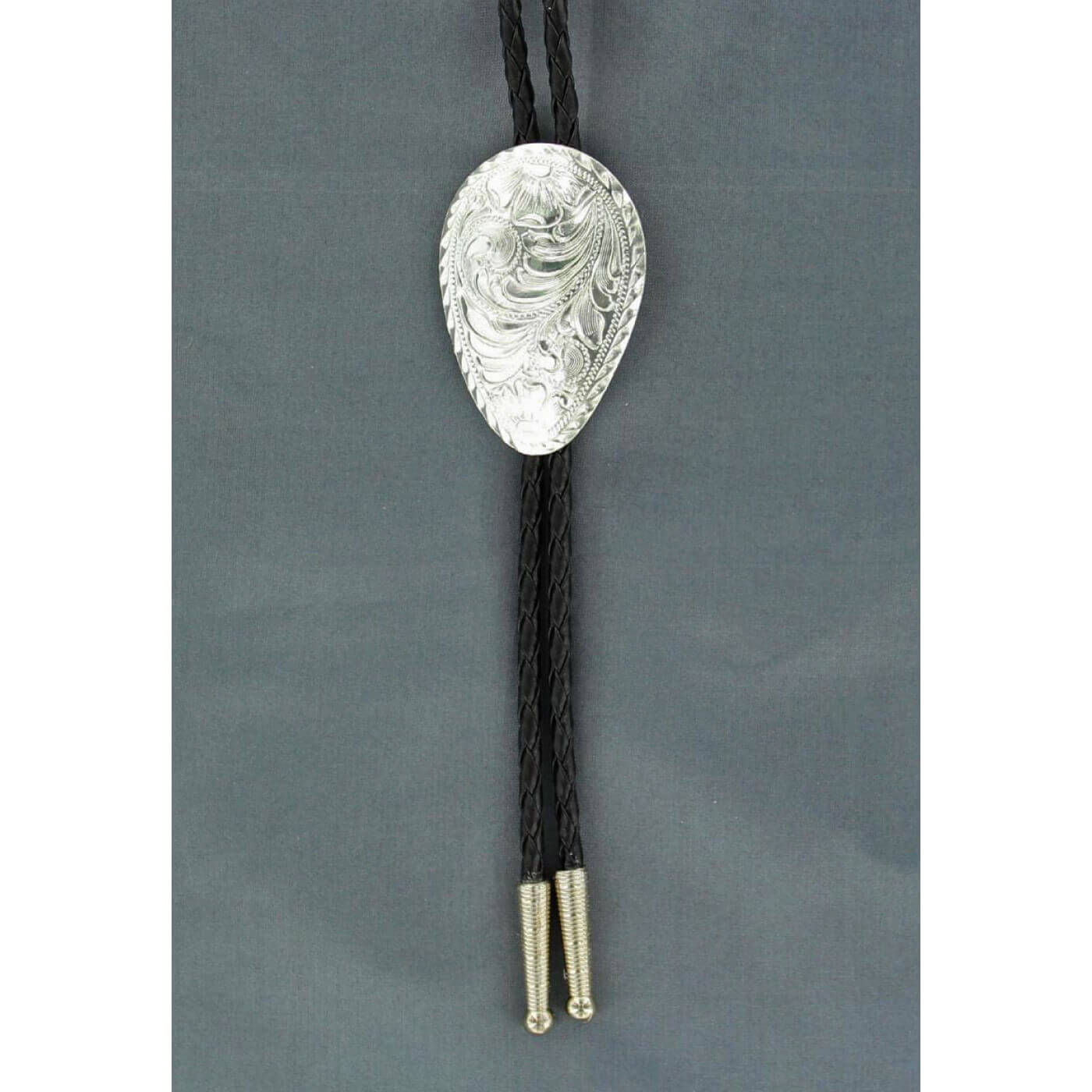 Add some flair to your western wear! Bolo tie features a black braided rope with silver tips accented with a shiny silver oval western floral engraved Concho. Adult bolo-36" long. Sterling Silver Plated.