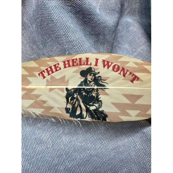 Wooden product with 'The Hell I Won't' text and horse design on a textured fabric background