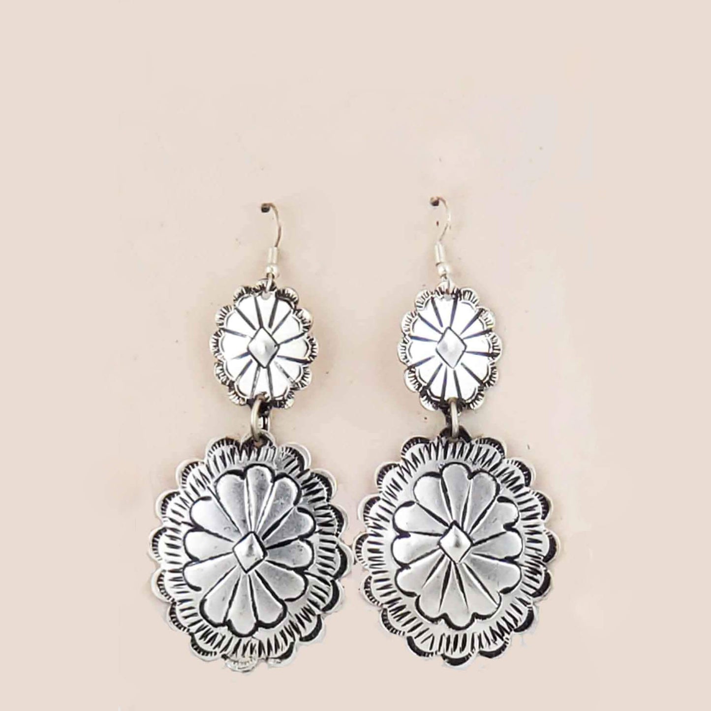 Silver floral earrings on a beige background