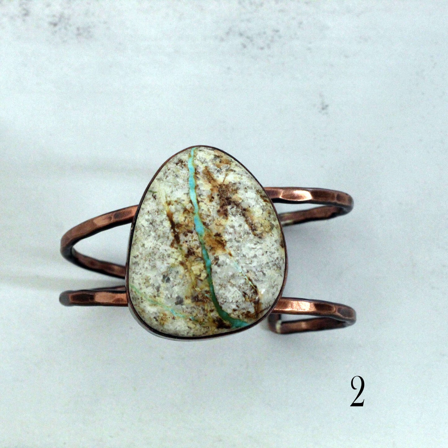 Copper ring with a large, textured stone on a light gray background