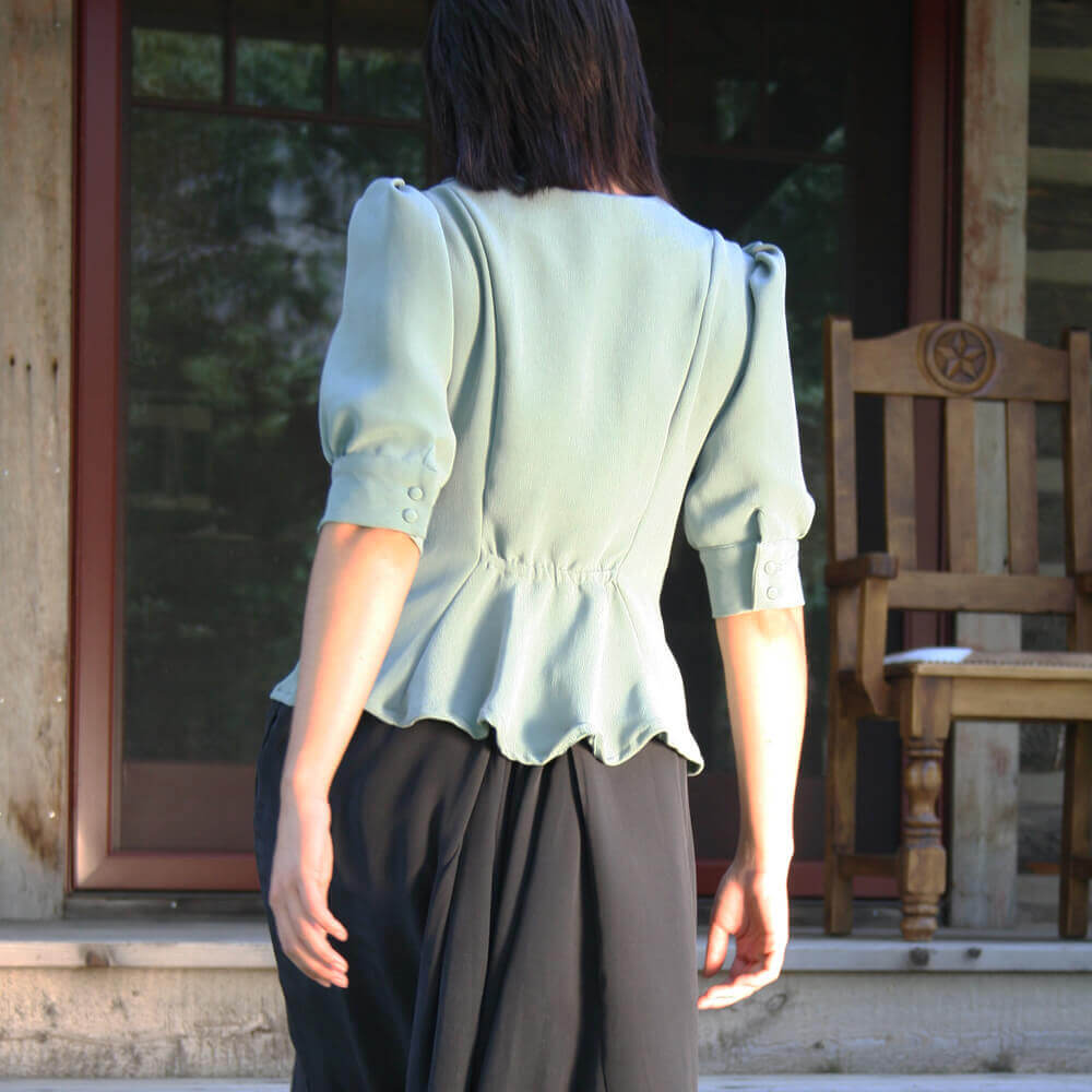 Back view of the chic Ella Country Blouse featuring fitted princess seams and a peplum design in soft green.