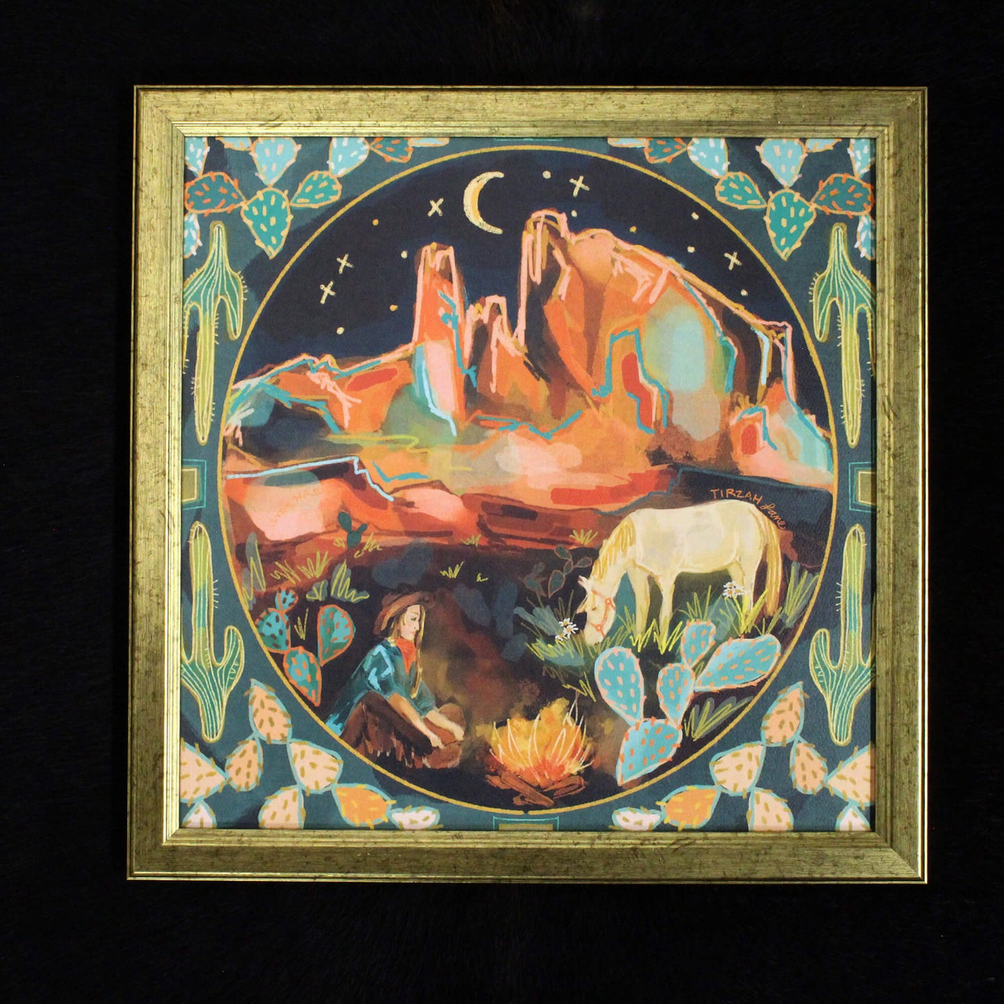 Framed artwork of a desert landscape with mountains, a horse, and a person by a campfire.