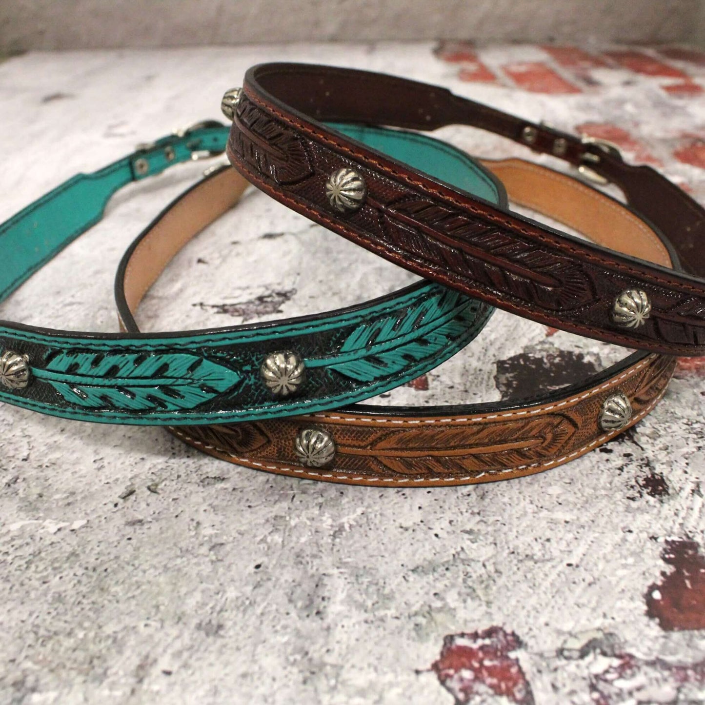 Leather western hatband embossed in a feather design with studs and buckle closure.