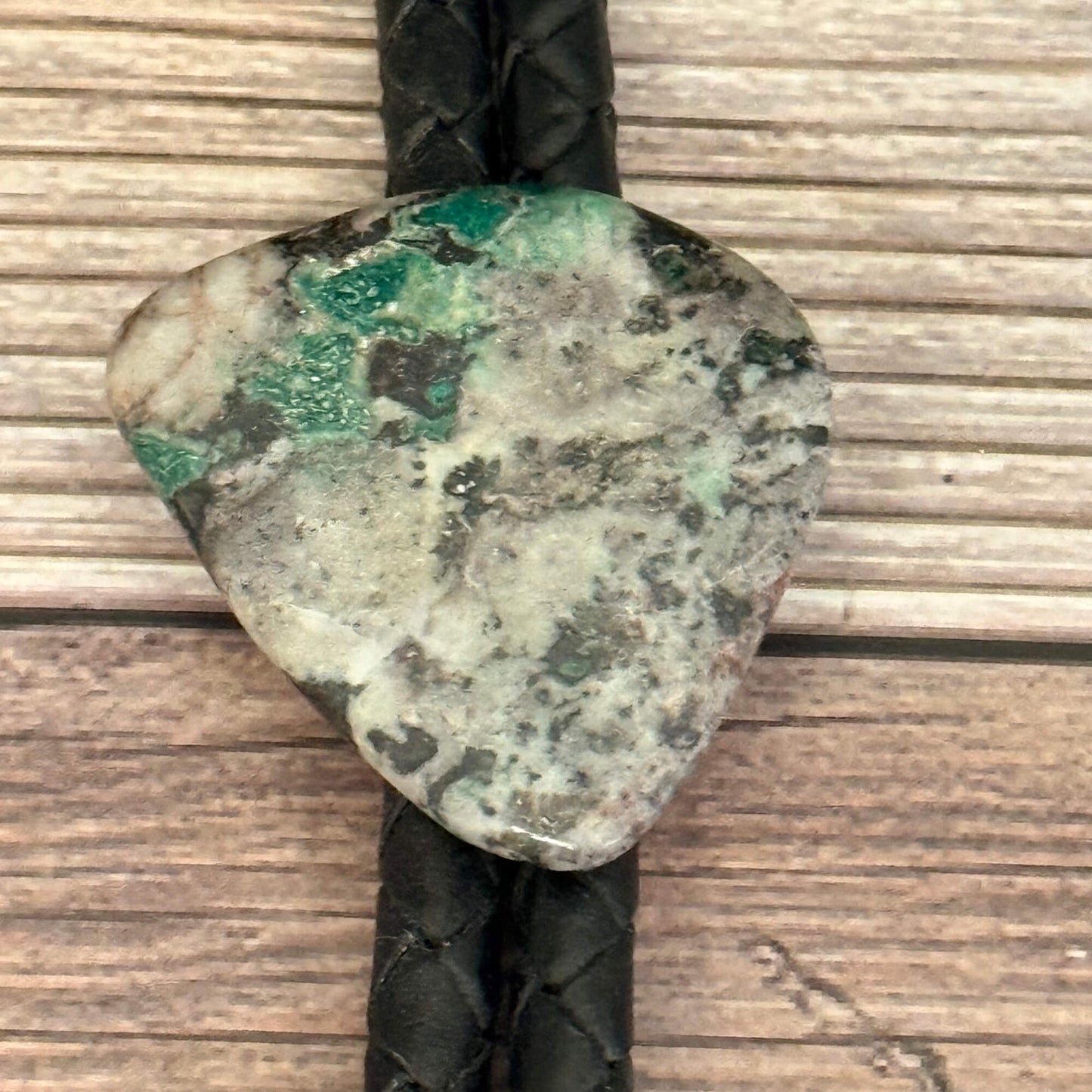 Polished stone with green and black patterns on a wooden surface