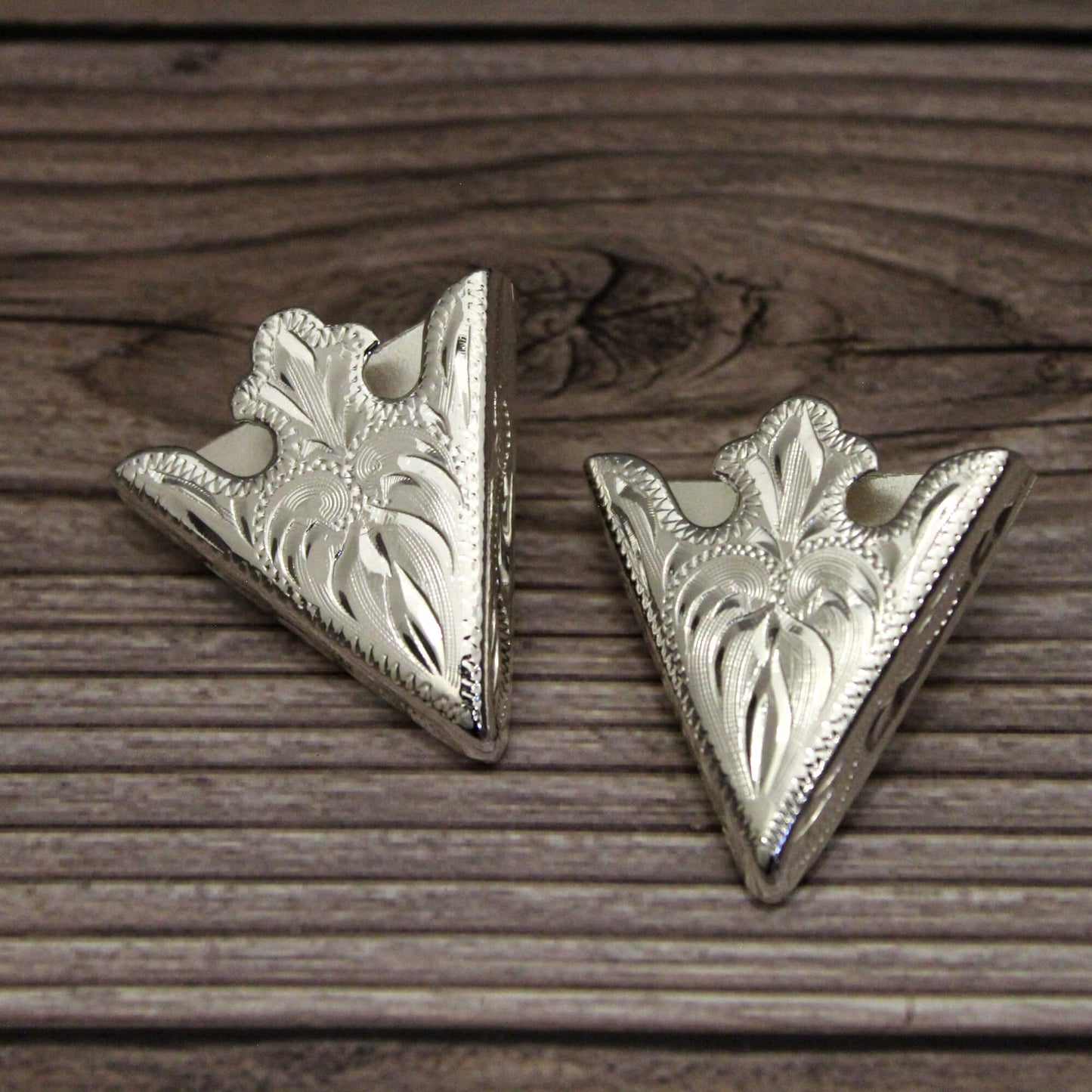 Two silver triangle-shaped decorative items on a wooden surface