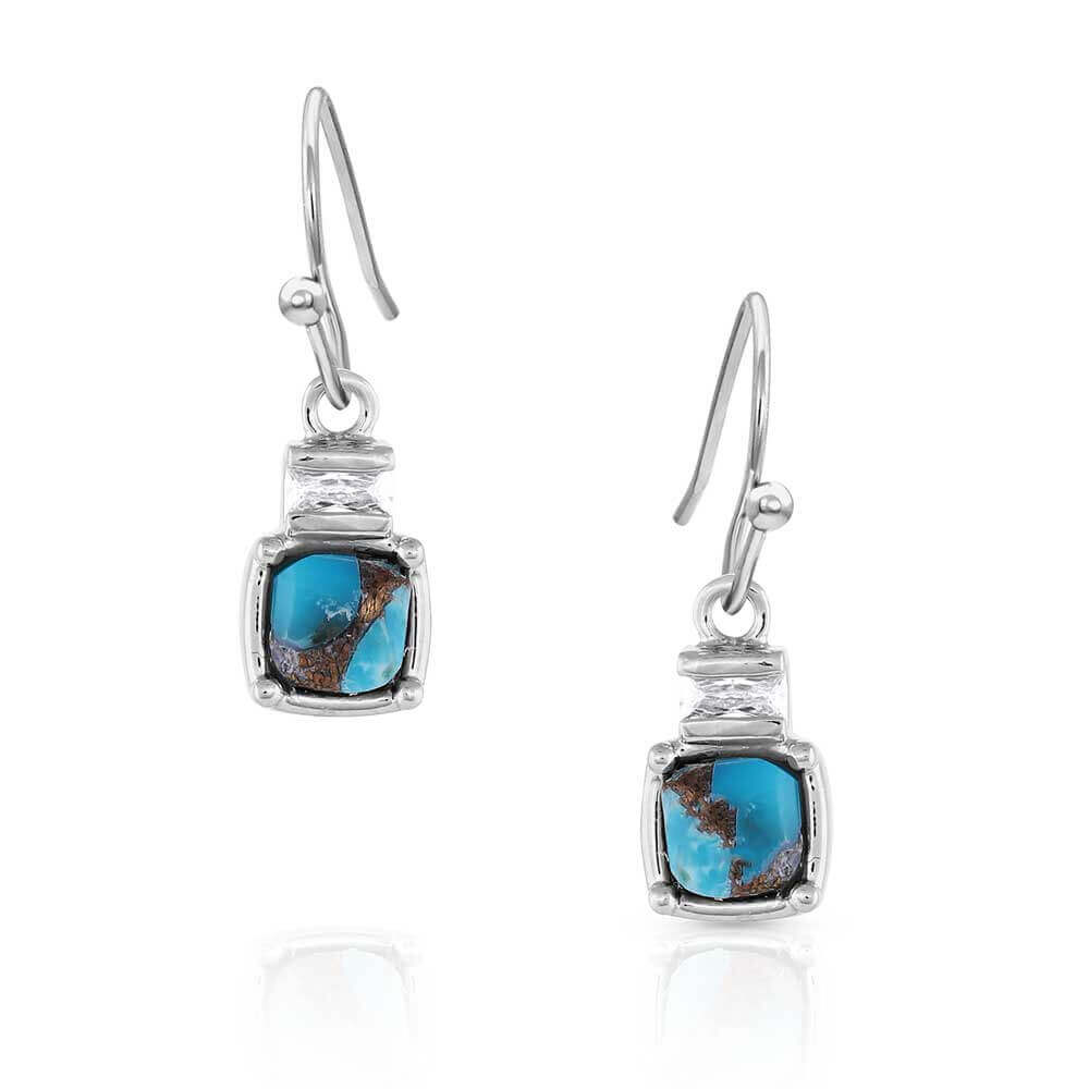 A lovely, compressed turquoise with copper stone is the center of attention for the Golden Rush Turquoise Earrings. The turquoise stone sits in the square silver setting of these earrings. A square silver design above the stone adds to the simplicity of the earrings and secures the earrings to a hypoallergenic French hook.
