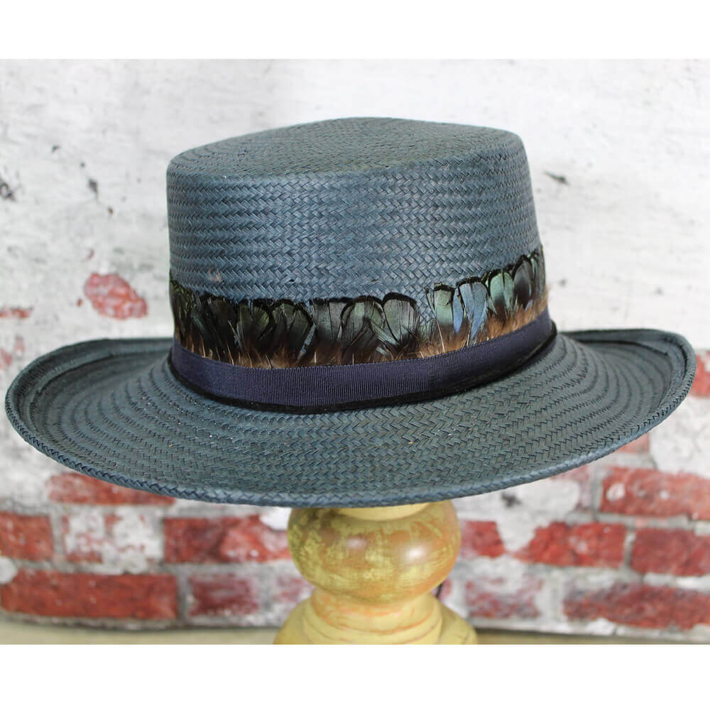 Unique vintage style hat made of navy straw with a gambler's shape crown in a 3-3/4" brim and crown. Brim is adorned in small peacock colored feathers with a black suede band chin cord with the ends wrapped in a feather. Hat is one size fits most with an inside adjustable band.