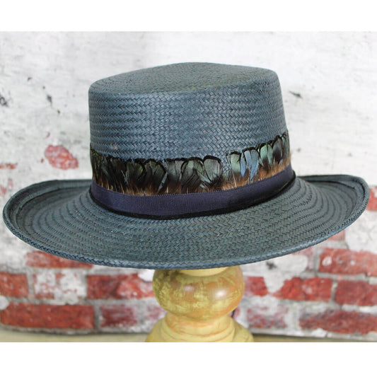 Unique vintage style hat made of navy straw with a gambler's shape crown in a 3-3/4" brim and crown. Brim is adorned in small peacock colored feathers with a black suede band chin cord with the ends wrapped in a feather. Hat is one size fits most with an inside adjustable band.