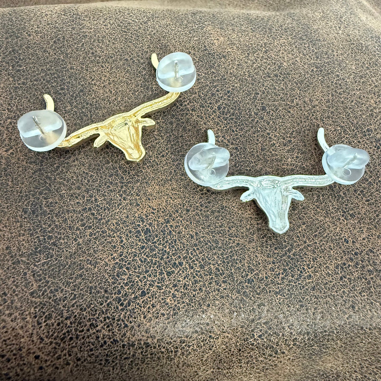 Two deer head antler pins on a textured surface