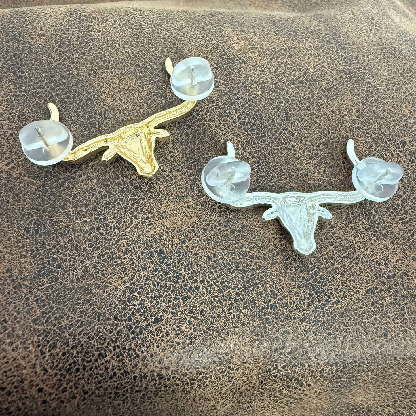 Two deer head antler pins on a textured surface