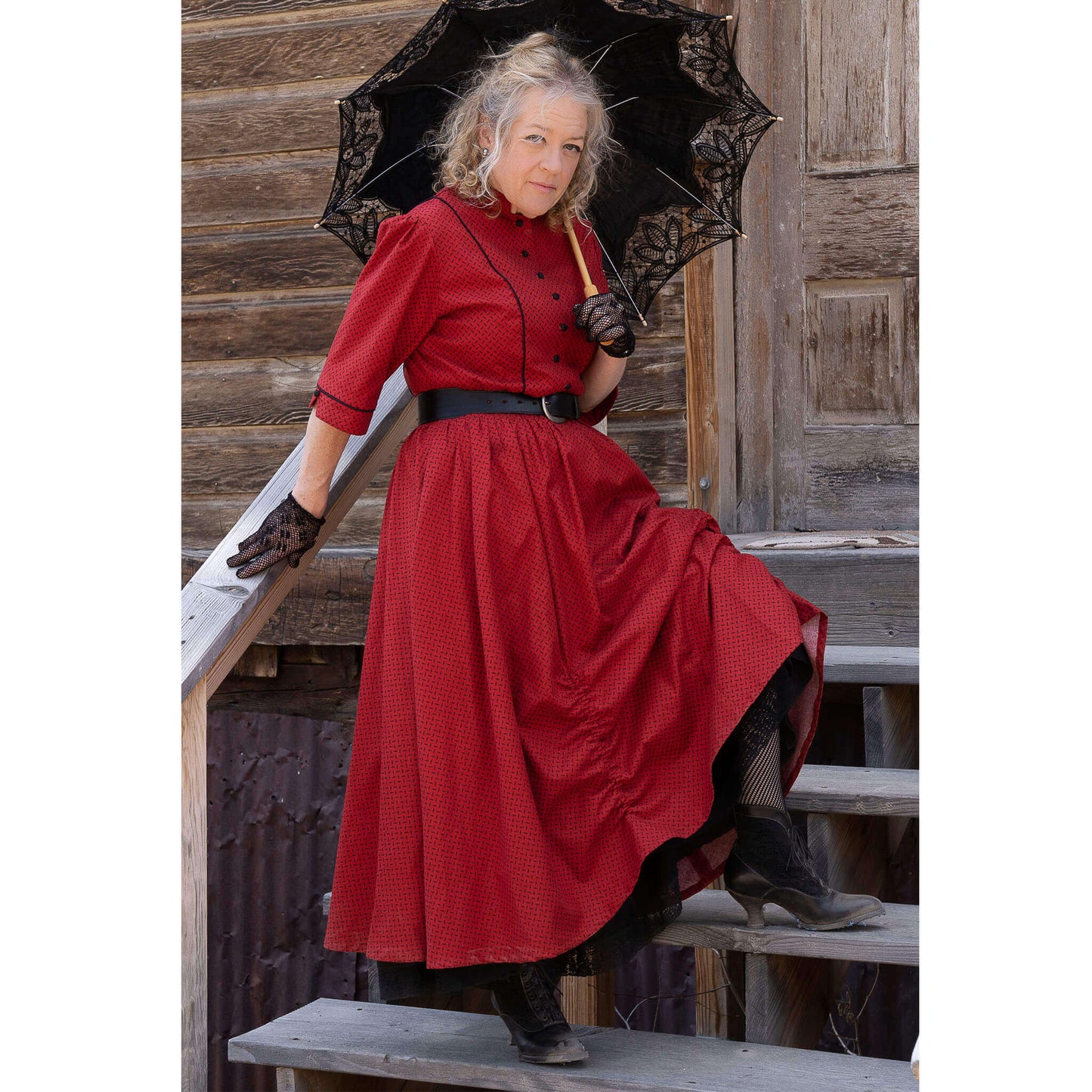 Woman in a red Old West saloon dress holding an umbrella, showcasing a vintage style with modern touches.