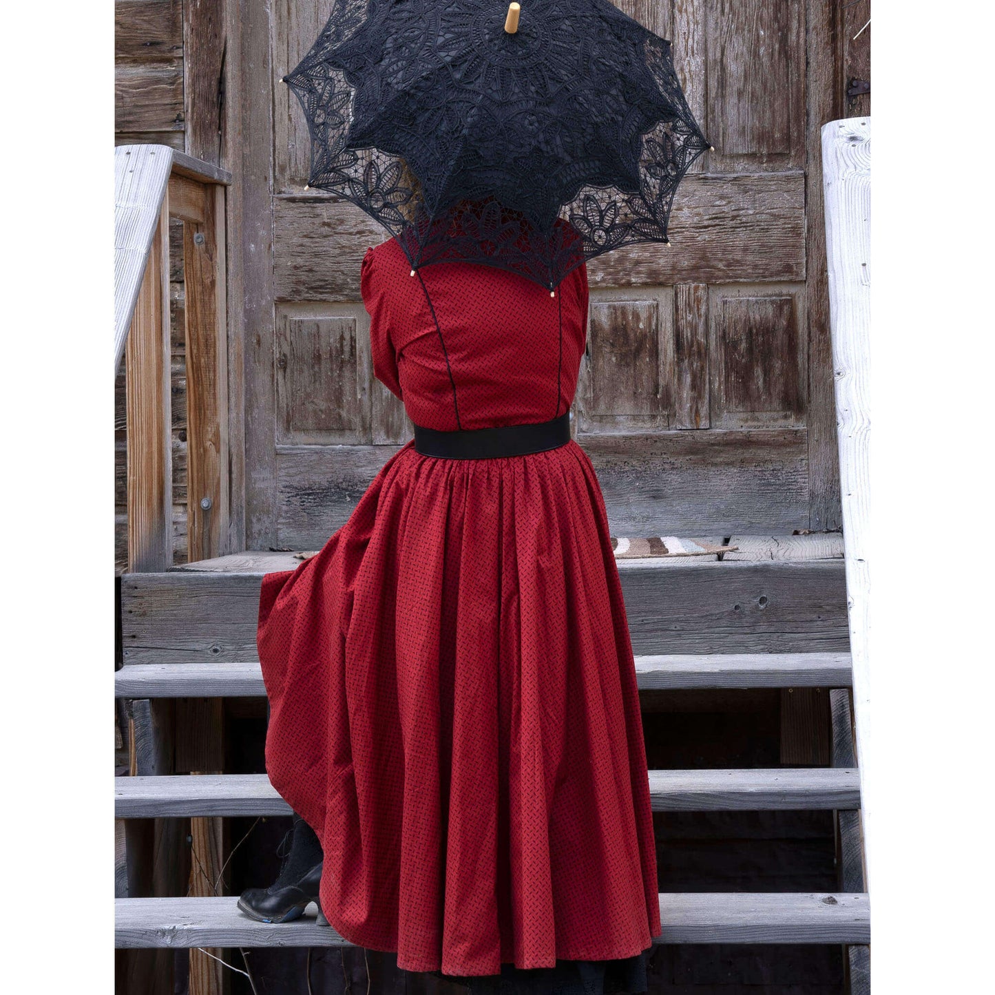 Mattie Mae Old West Saloon Dress in red with fitted bodice and gathered skirt, complemented by a black lace parasol.