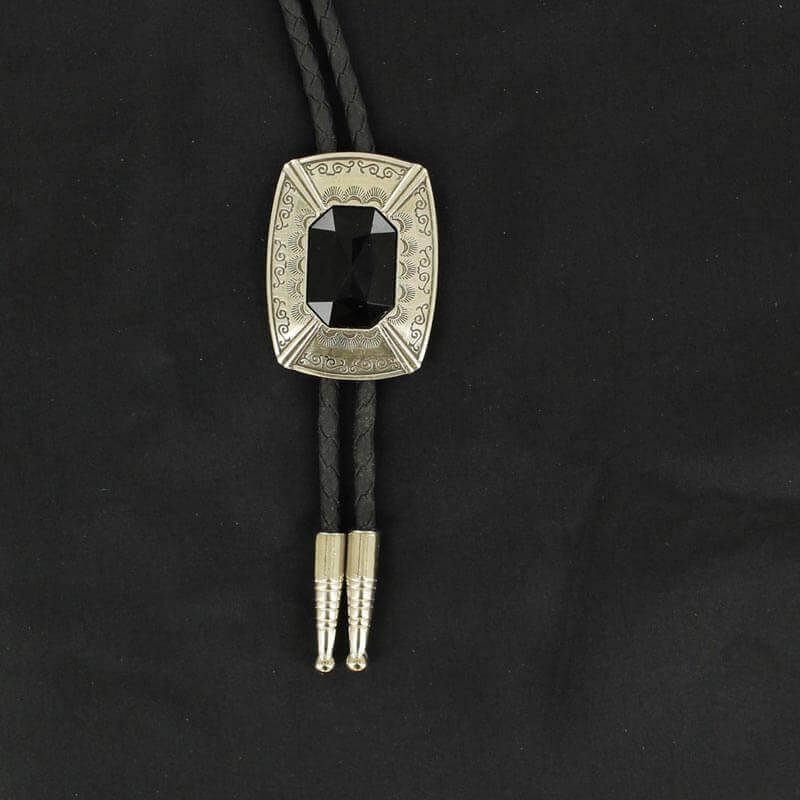 This Bolo tie has a silver rectangle engraved with detail and a black centered stone. This handsome bolo tie is a great addition that will go with many different attires.
