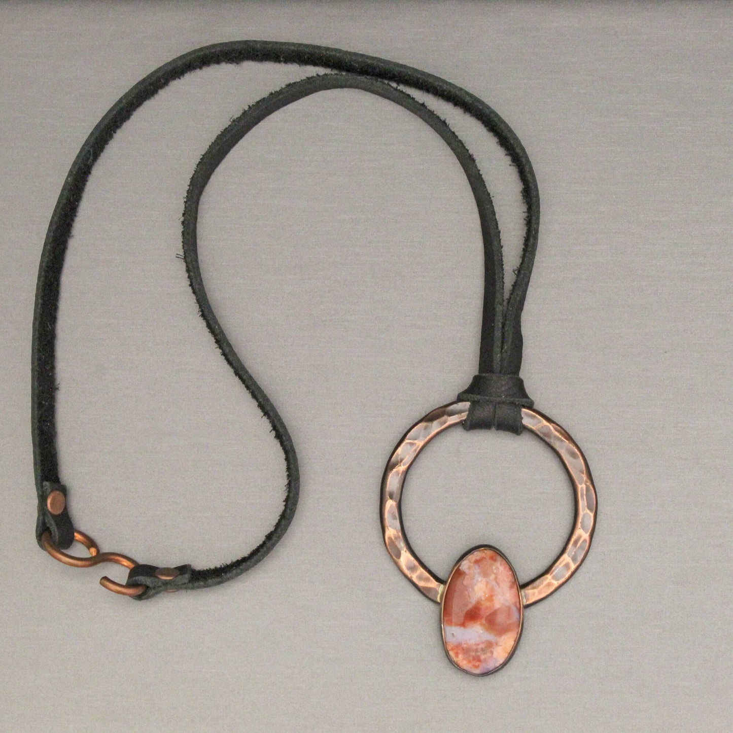 Necklace with a copper pendant on a gray background