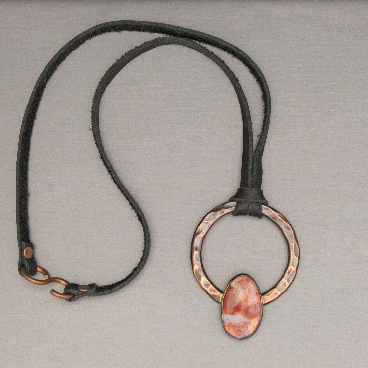 Necklace with a copper pendant on a gray background