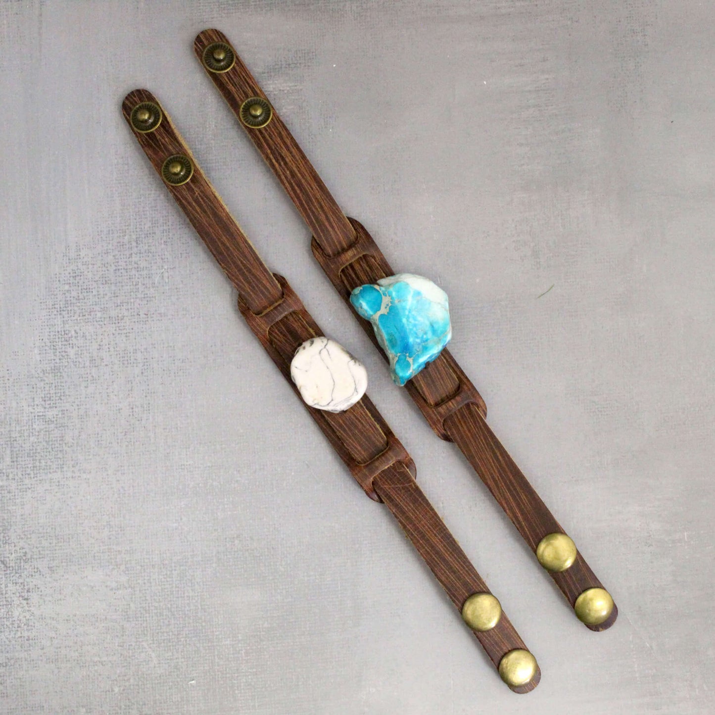Two wooden bracelets with stone inlays on a gray background