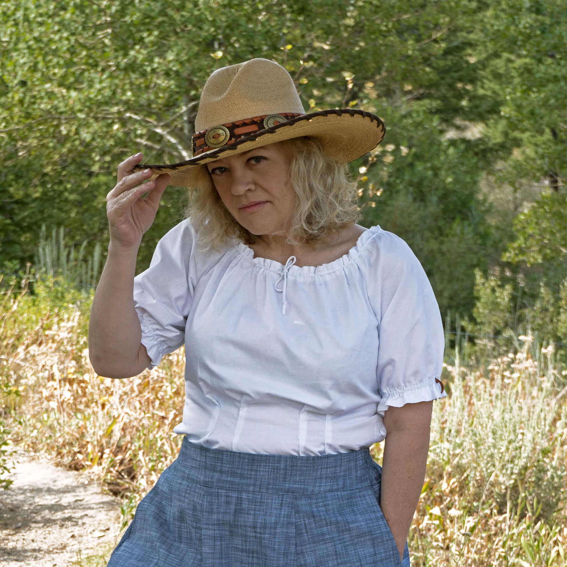 Woman wearing Olmstead Women's Western Peasant Blouse and a cowboy hat in a natural outdoor setting.