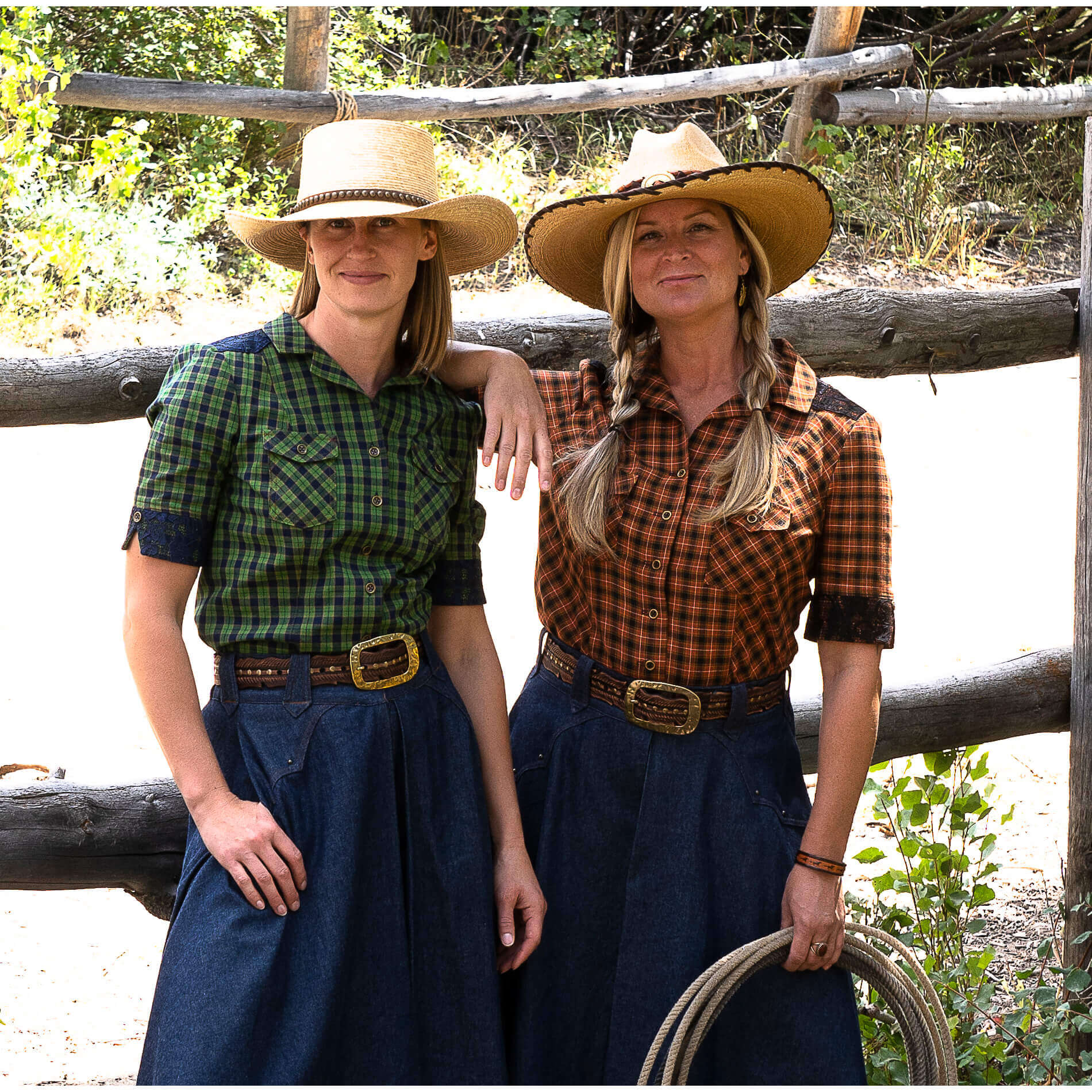 Two women wearing Rodeo Round-Up Ladies Shirts in a western setting, showcasing stylish plaid designs and cowboy hats.