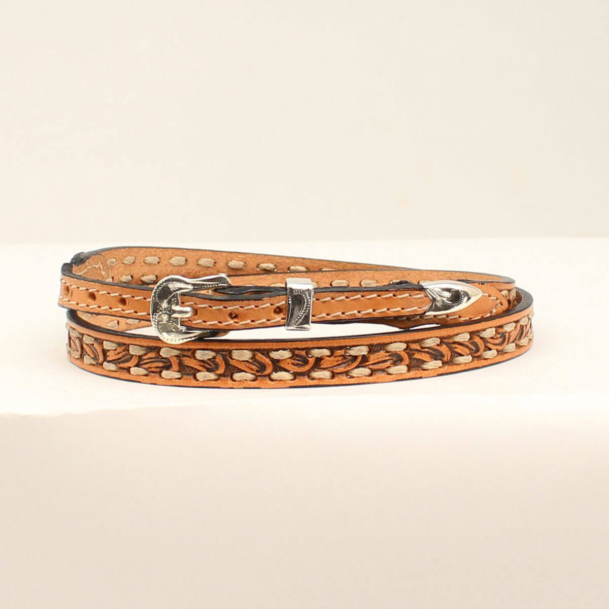 Brown leather hatband with silver buckle on a beige background