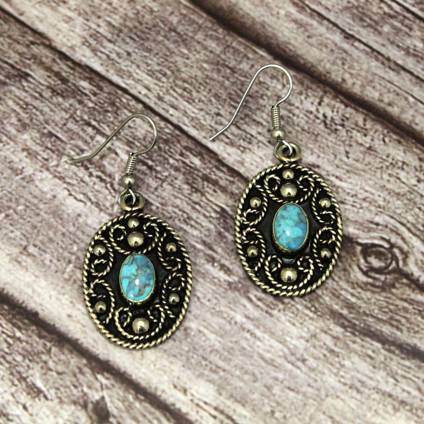 Western dangle earrings for cowgirls and anyone who loves the western lifestyle. Intricate western rope design on an oval pendant with turquoise center adding a pop of color to any outfit. Crafted with French hooks, they offer a secure fit while making a bold fashion statement. Hangs down about 2" with the oval measuring 1-1/8" x 7/8".