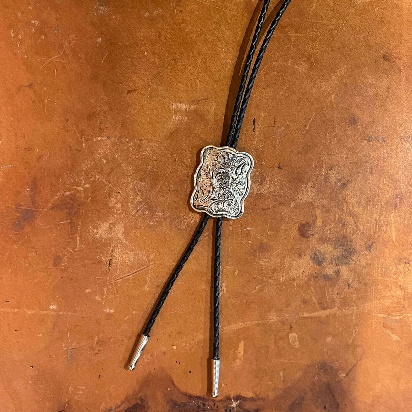 These western Bolo tie slides are a lovely shiny silver in a large scalloped Concho design. It's a beautiful classic style western bolo tie. Choose the plain silver style or antique gold and silver with horsehead in center. Black braided cord with silver tips; Medallion dimensions: