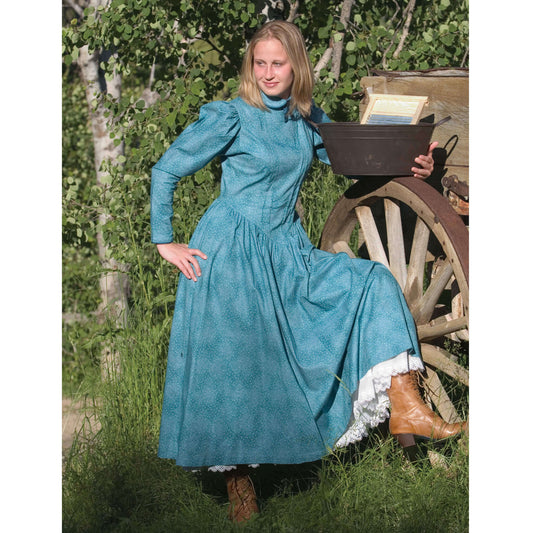 Model in a vintage school marm dress with puffed sleeves and boots, set against a rustic backdrop.