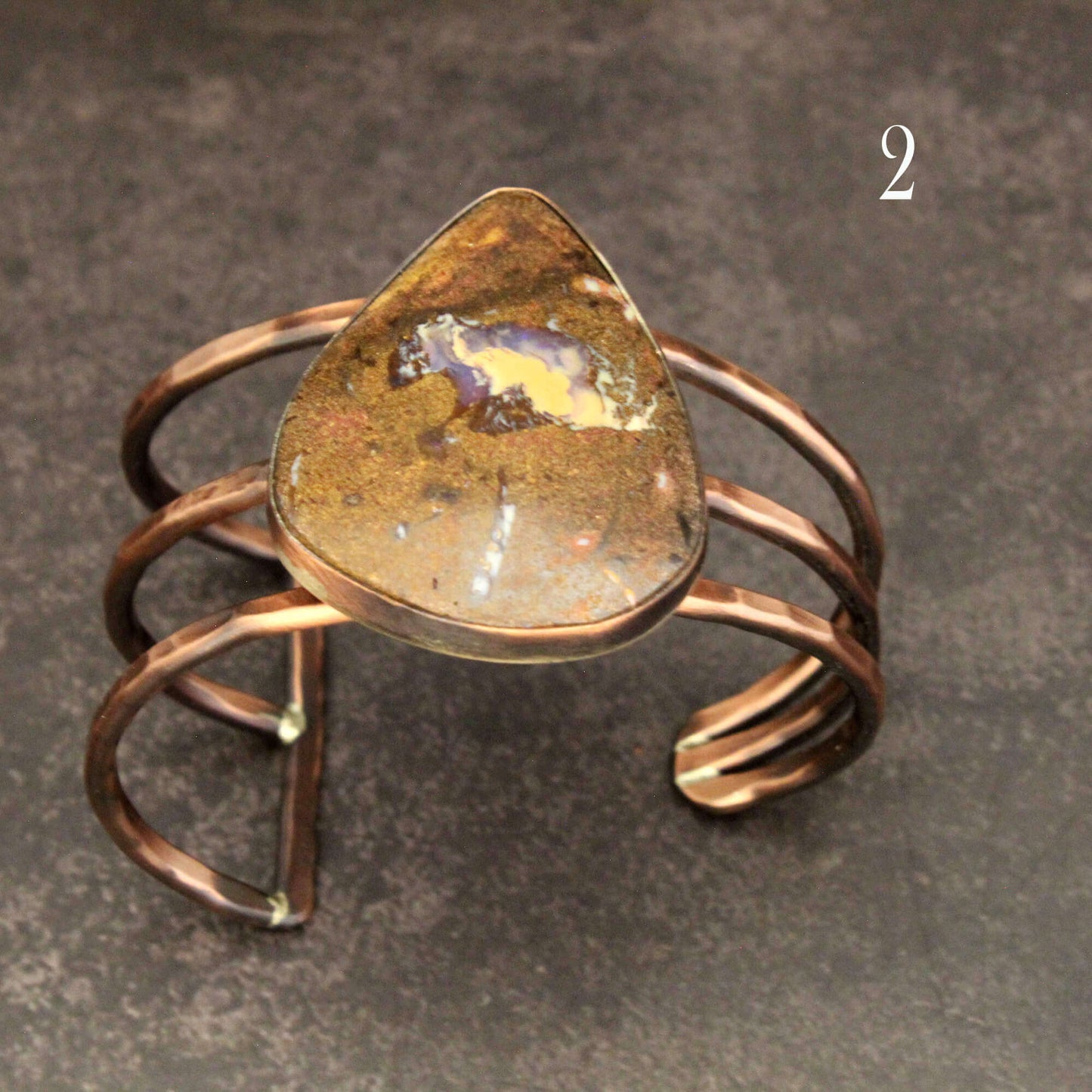 Copper ring with a large teardrop-shaped stone on a gray background