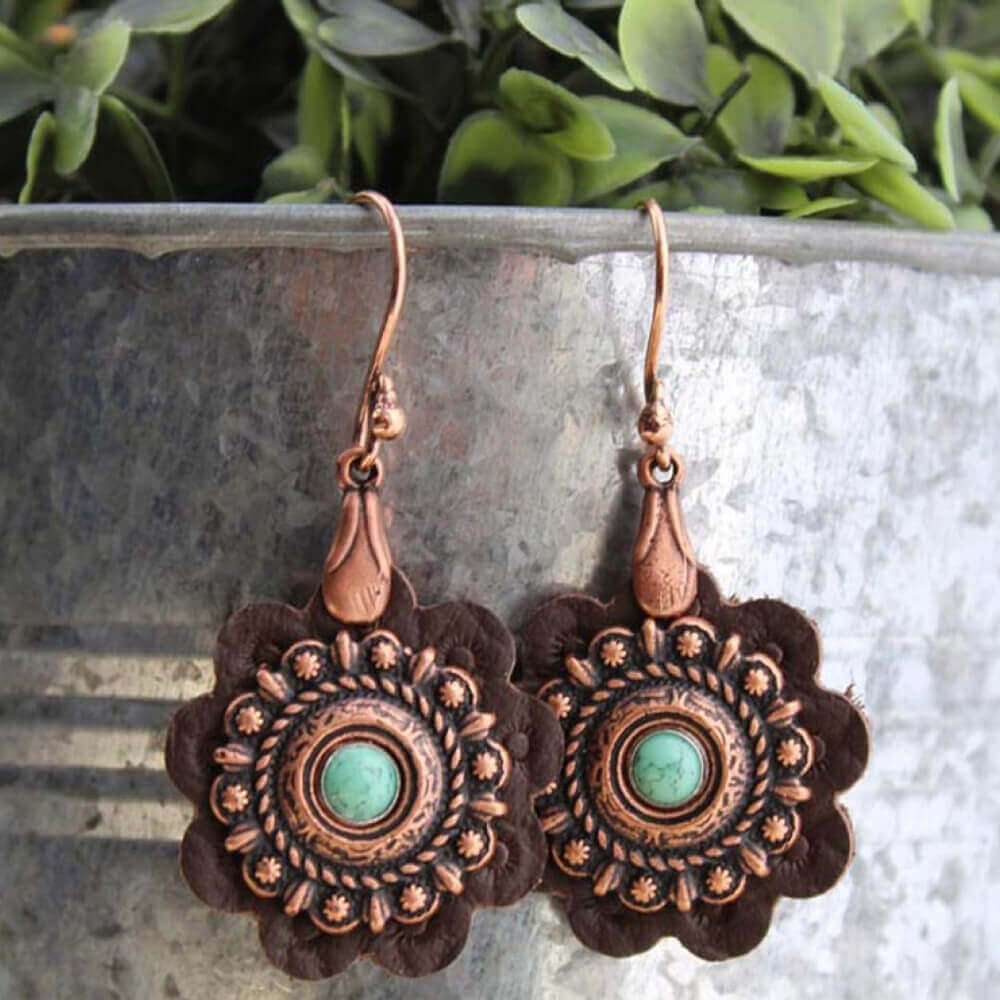 When you want jewelry that is as unique as you are, look no further than these hand cut leather rosette earrings. The brown leather is decorated with a copper Concho and turquoise center hanging from a copper wire hook. Approximately 1” diameter.