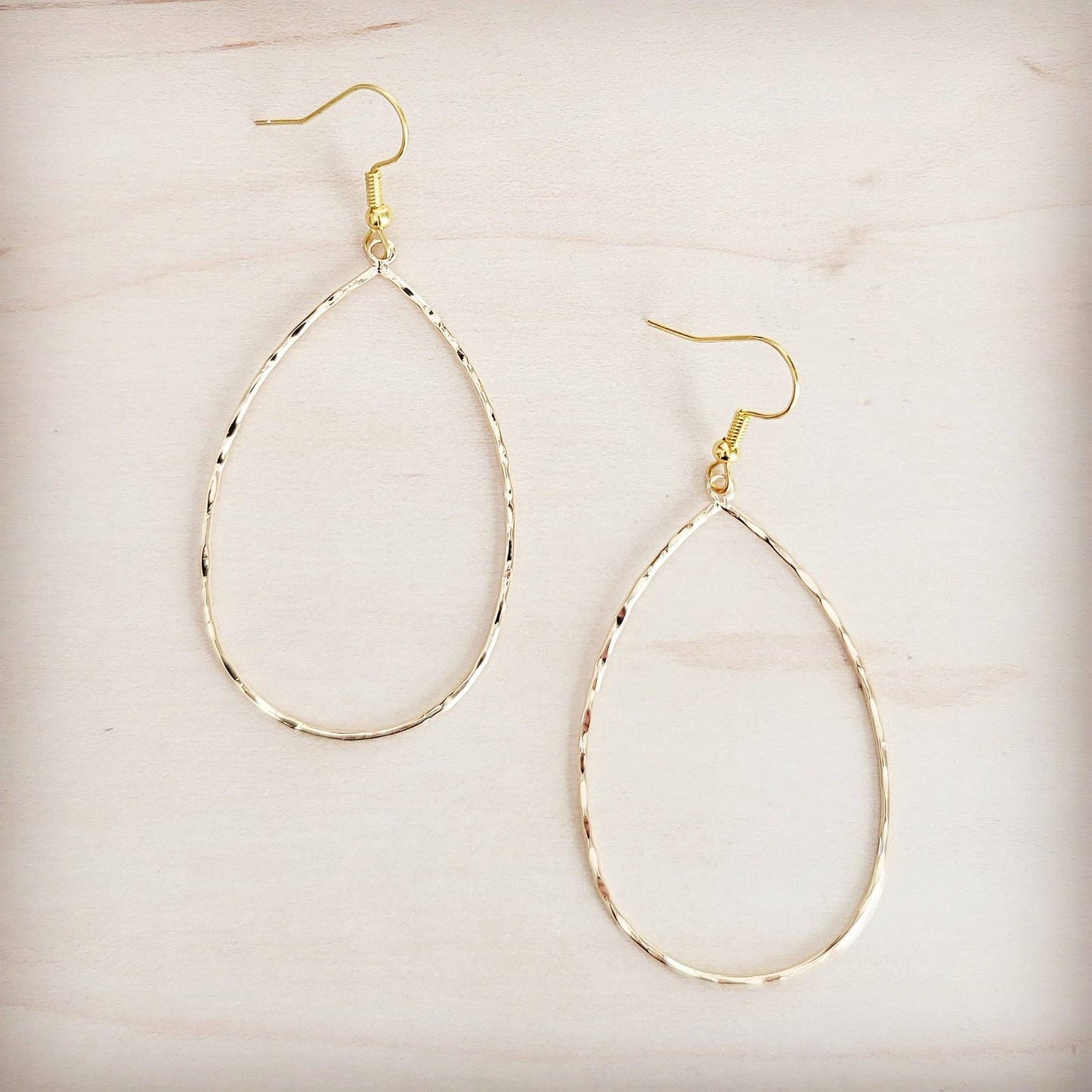 Gold hoop earrings on a light beige background