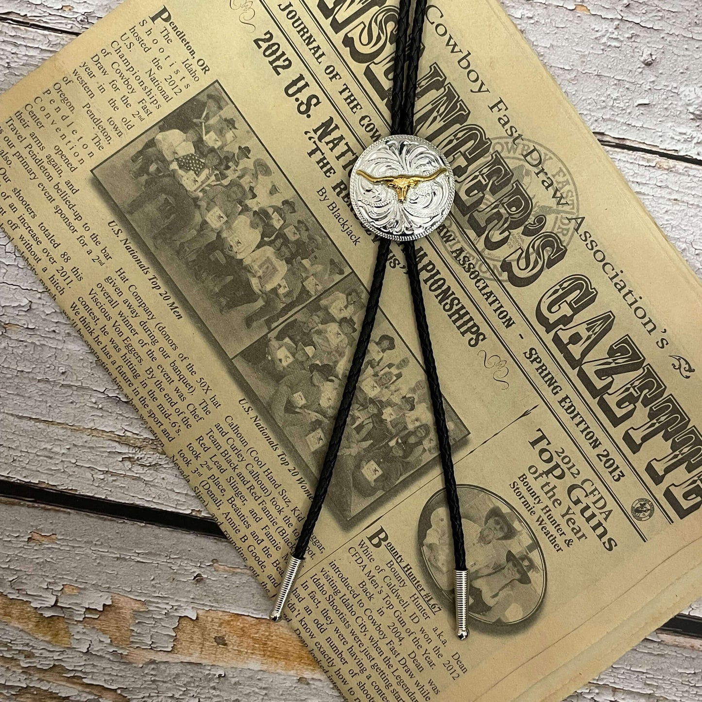 This men's western bolo tie features a round silver Concho with a gold longhorn motif. Black braided leather beautifully compliments the two-toned Concho.