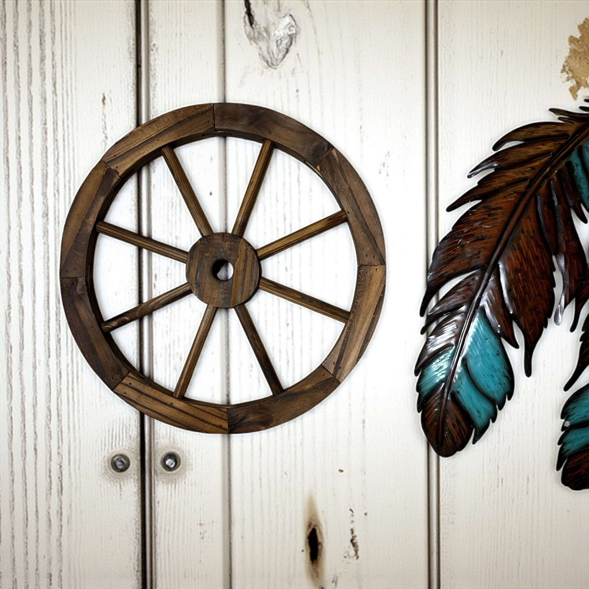 Old West Wooden Decorative Wagon Wheel displayed on a rustic wall with a colorful feather decor.