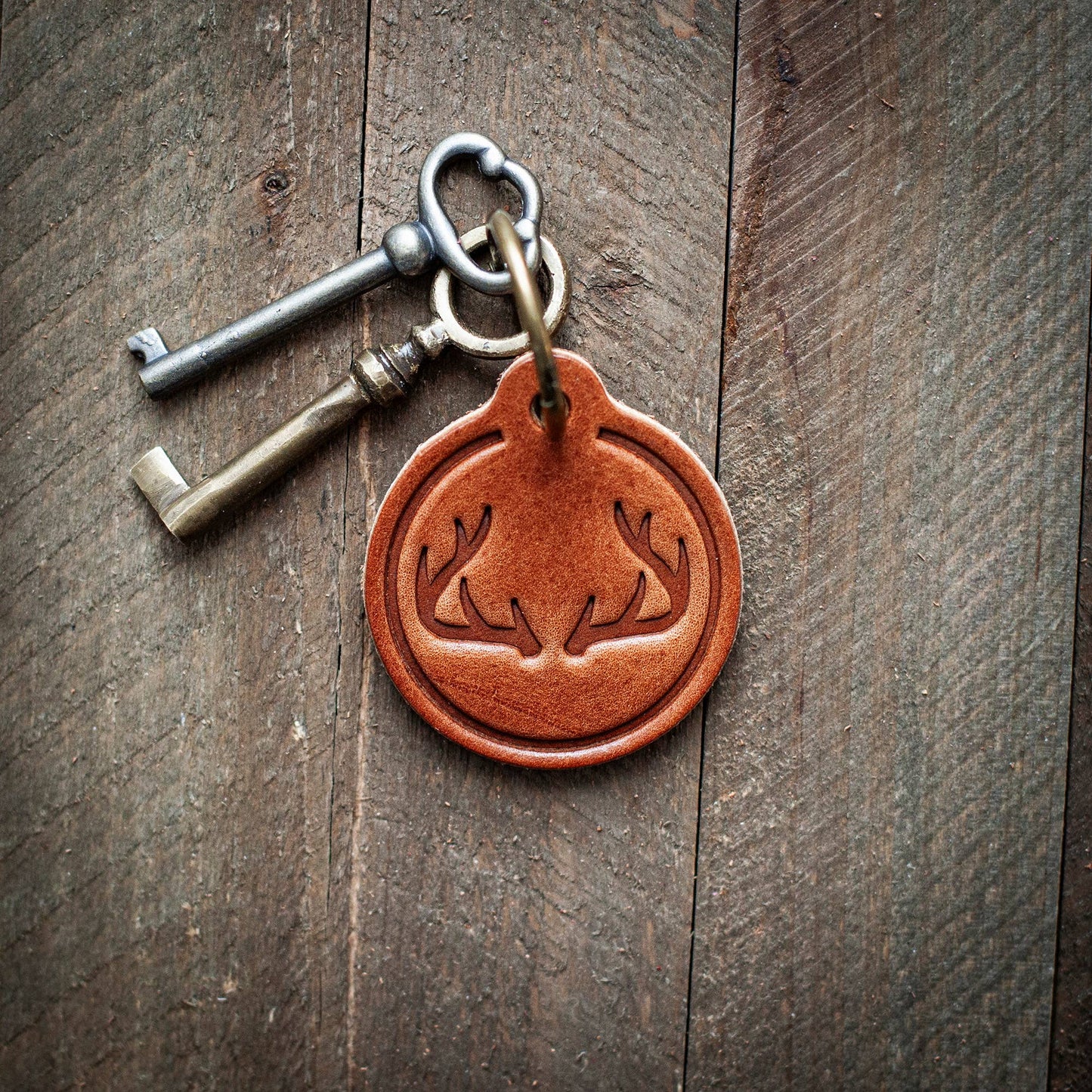 Keychain with two keys and a leather tag on a wooden surface