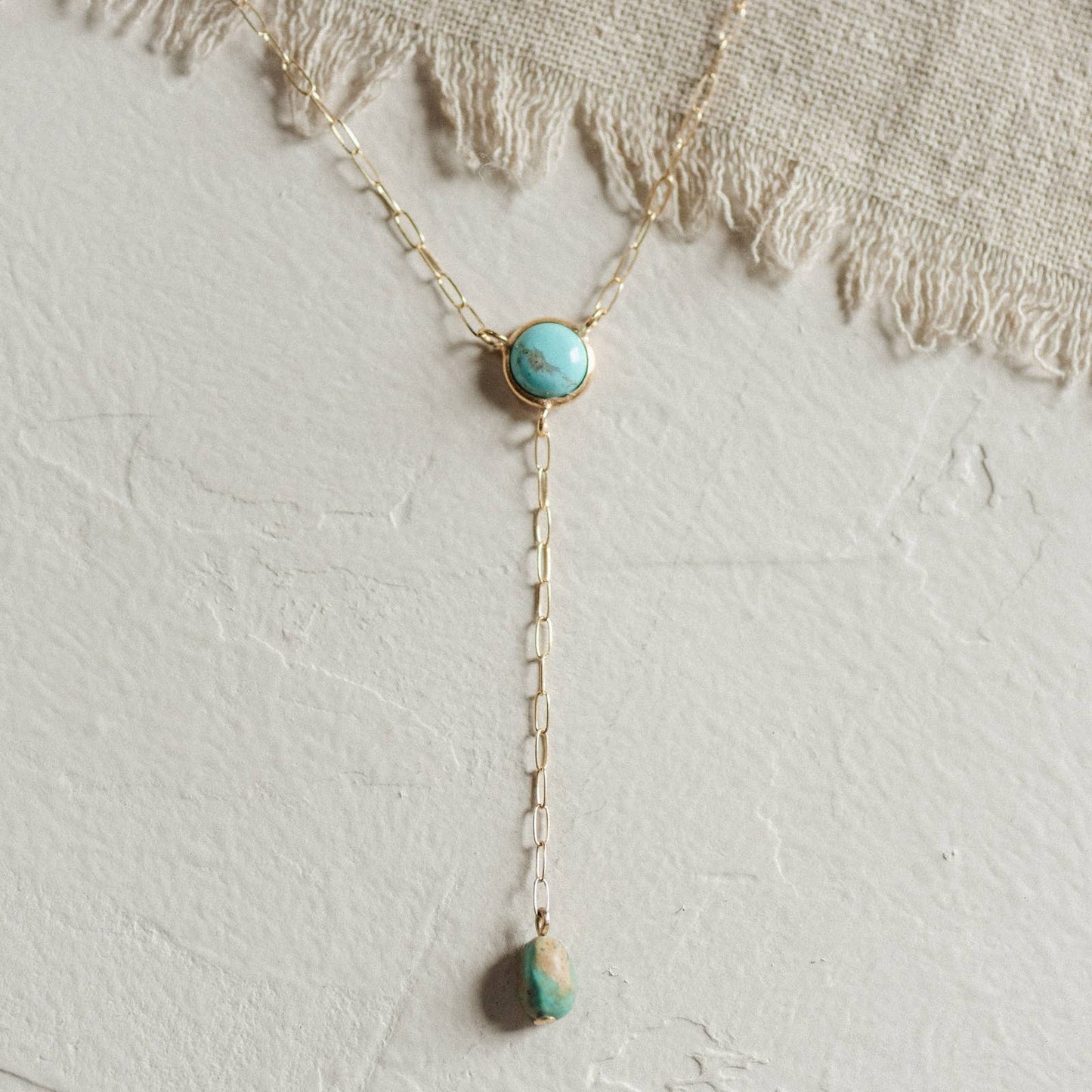 Turquoise stone necklace on a textured white background