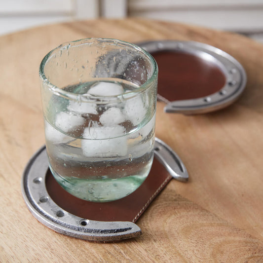 These unique coasters will bring the essence of the wild west to your tables. Protect your surfaces from sweating drinks in style. Coasters are created with leather and aluminum horseshoes. Measurement: 2¼''W x 5''D x ¼''H