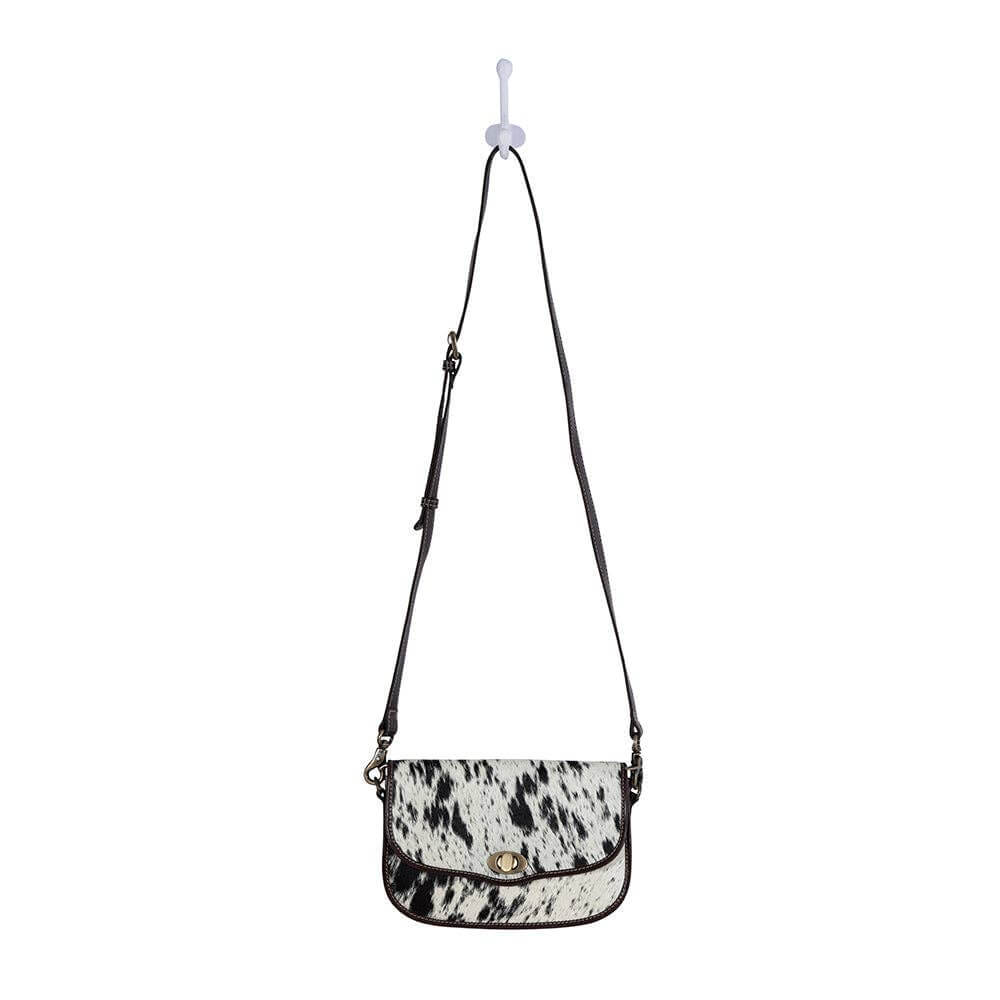 Black and white cow print crossbody bag on a white background